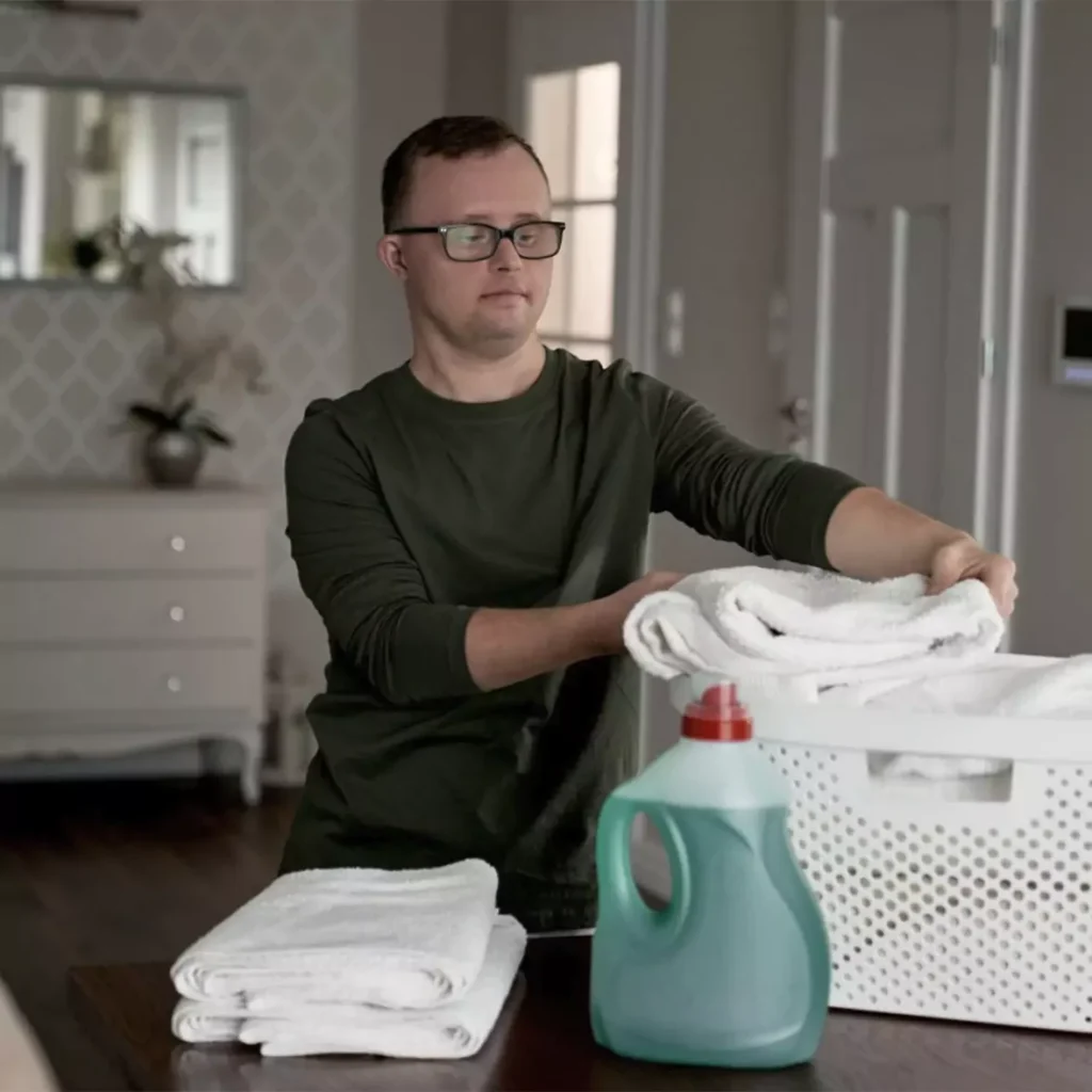 A down syndrome man folding laundry indoors