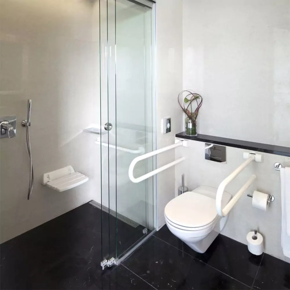 A bathroom with handicap railings in the shower and by the toilet