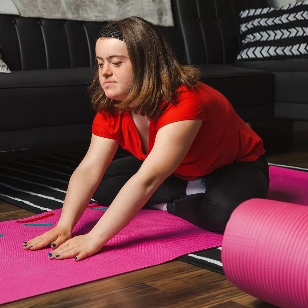 A down syndrome woman doing yoga indoors