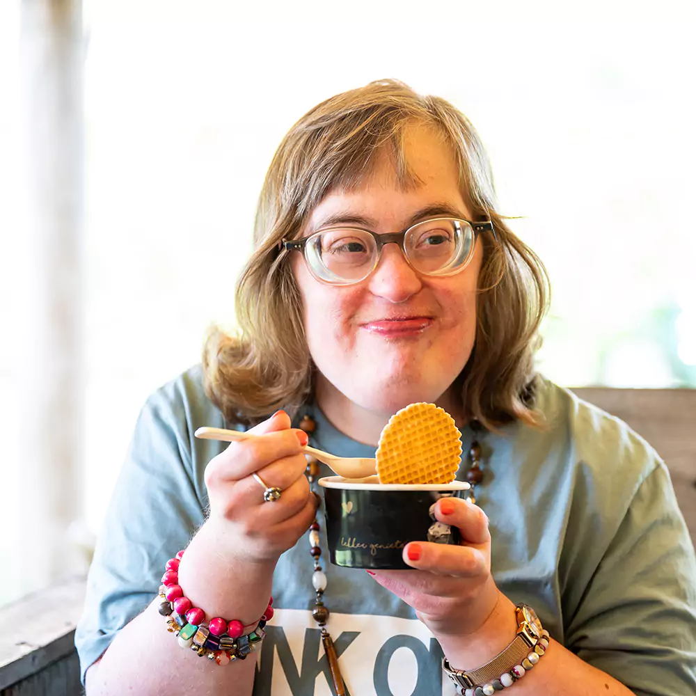 A down syndrome woman happy eating her ice cream as a cafe
