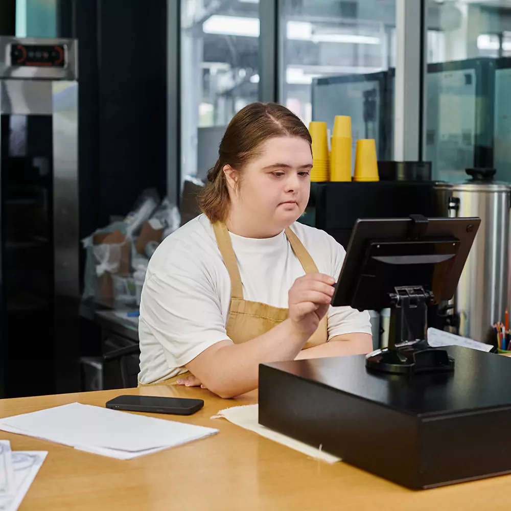 A down syndrome woman working as a cafe on the checkout