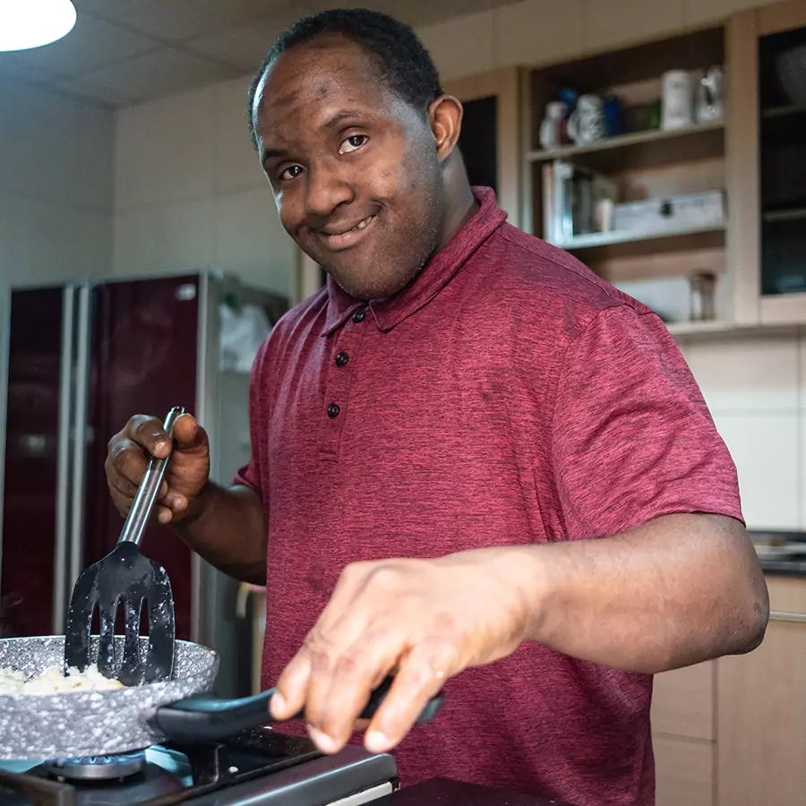A down syndrome man cooking something in the kitchen